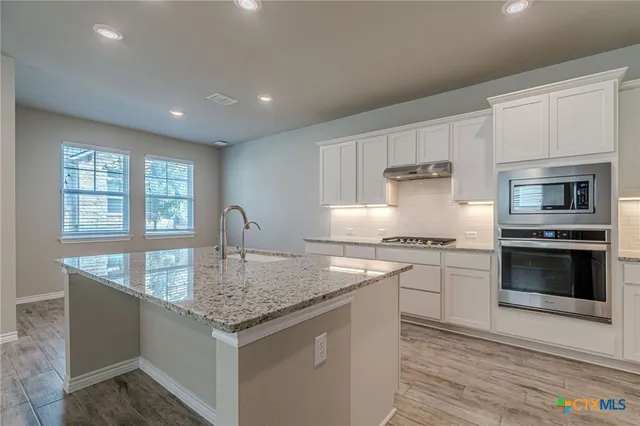 a kitchen with granite countertop stainless steel appliances a stove sink and microwave