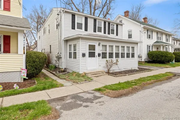 a front view of a house with a yard and potted plants