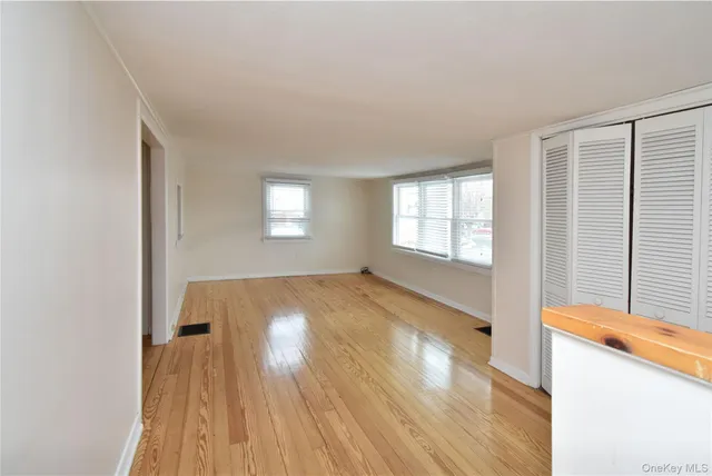 a view of empty room with window and wooden floor