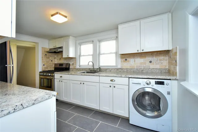a kitchen with granite countertop white cabinets and stainless steel appliances