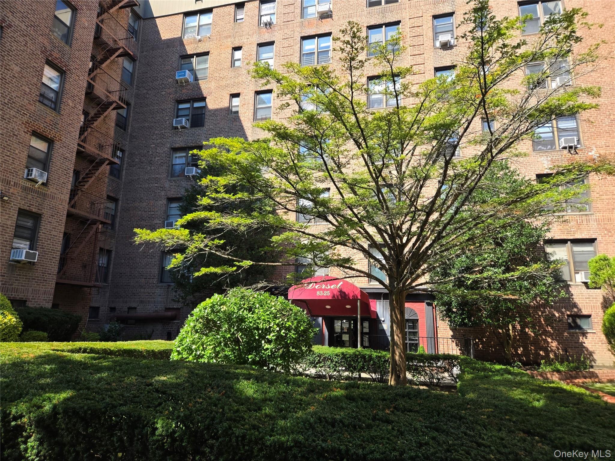 83-25 98th Street, Unit 1P Queens, NY 11421 - Photo 2 of 16 a front view of a multi story residential apartment building with yard and green space