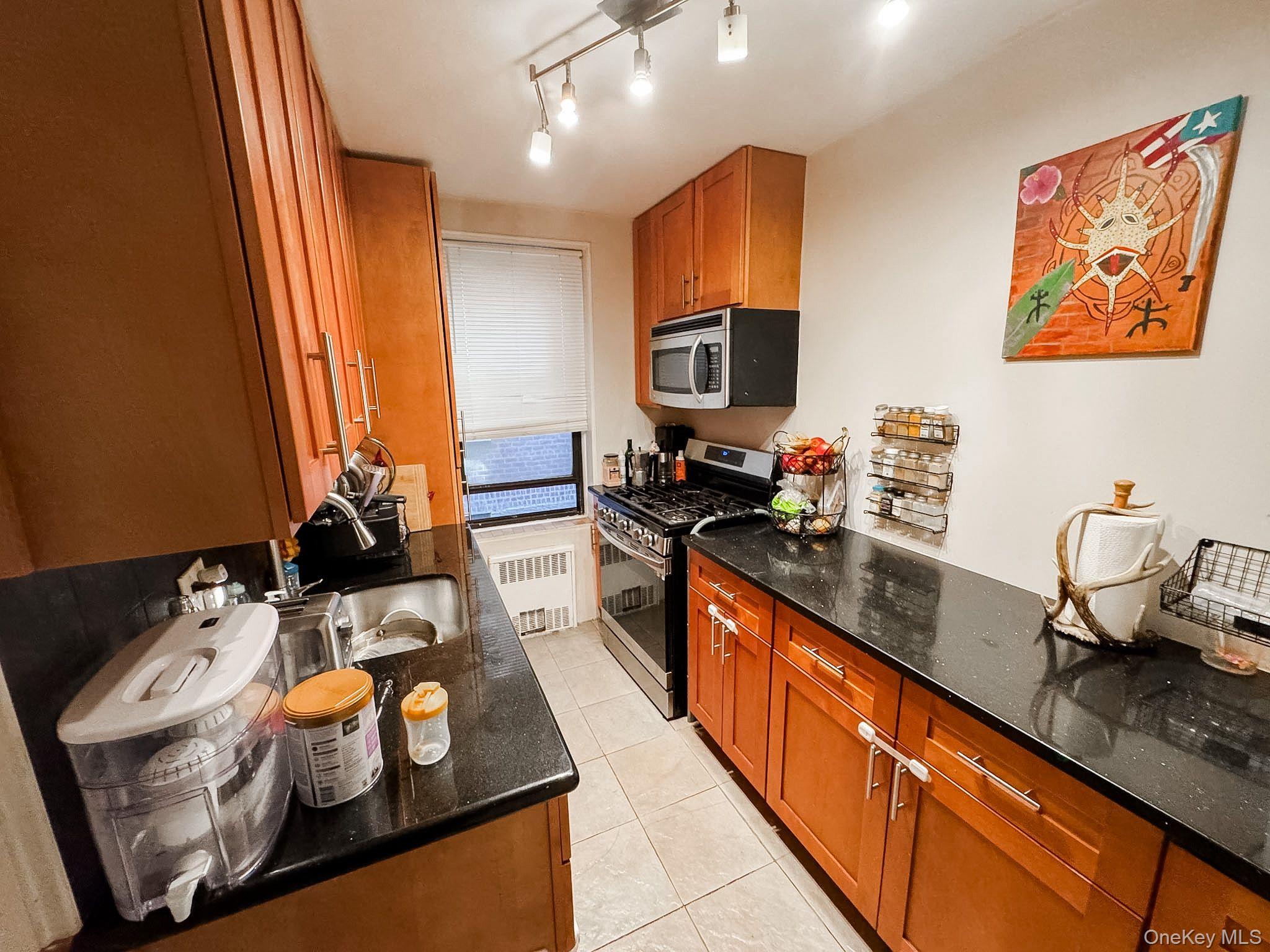 83-25 98th Street, Unit 1P Queens, NY 11421 - Photo 9 of 16 a kitchen with stainless steel appliances granite countertop a sink stove and refrigerator