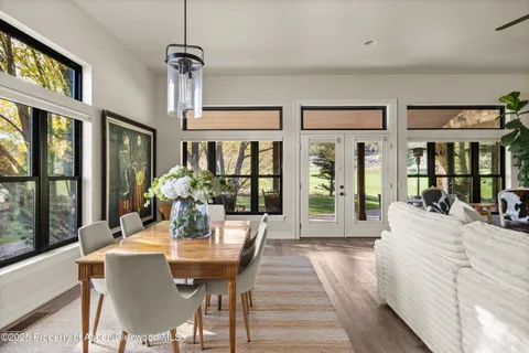 a view of a dining room with furniture wooden floor a chandelier and windows