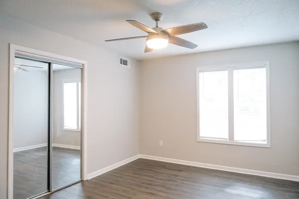 an empty room with wooden floor closet and windows