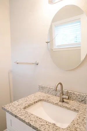 a bathroom with a granite countertop sink and a mirror