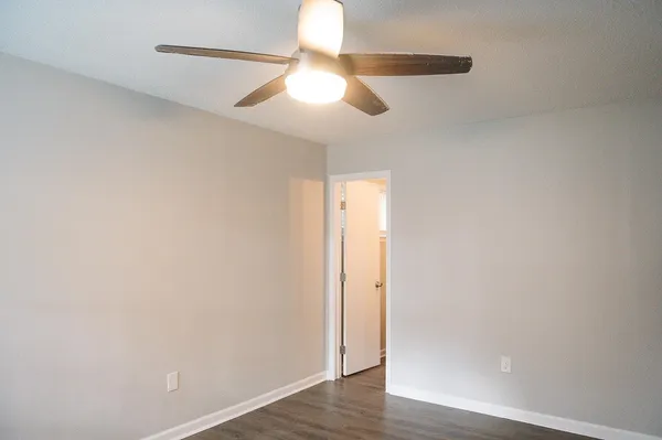 an empty room with wooden floor fan and window