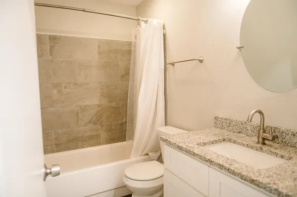 a bathroom with a granite countertop sink toilet and shower