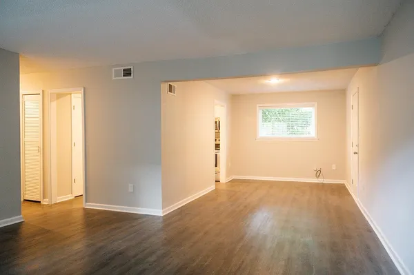 an empty room with wooden floor and windows