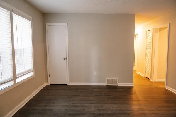 a view of an empty room with wooden floor and a window