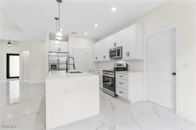 a kitchen with kitchen island a sink stainless steel appliances and white cabinets