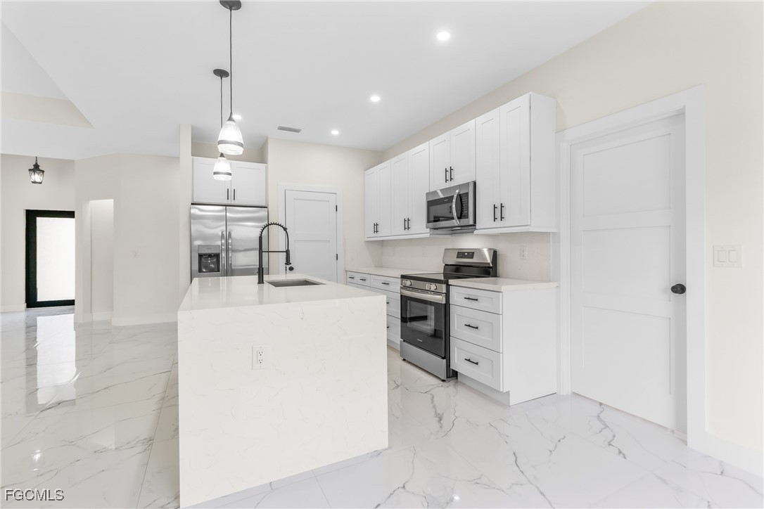 412 Fitch Avenue Lehigh Acres, FL 33972 - Photo 12 of 50 a kitchen with kitchen island a sink stainless steel appliances and white cabinets