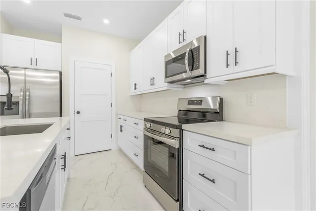 a kitchen with white cabinets and stainless steel appliances