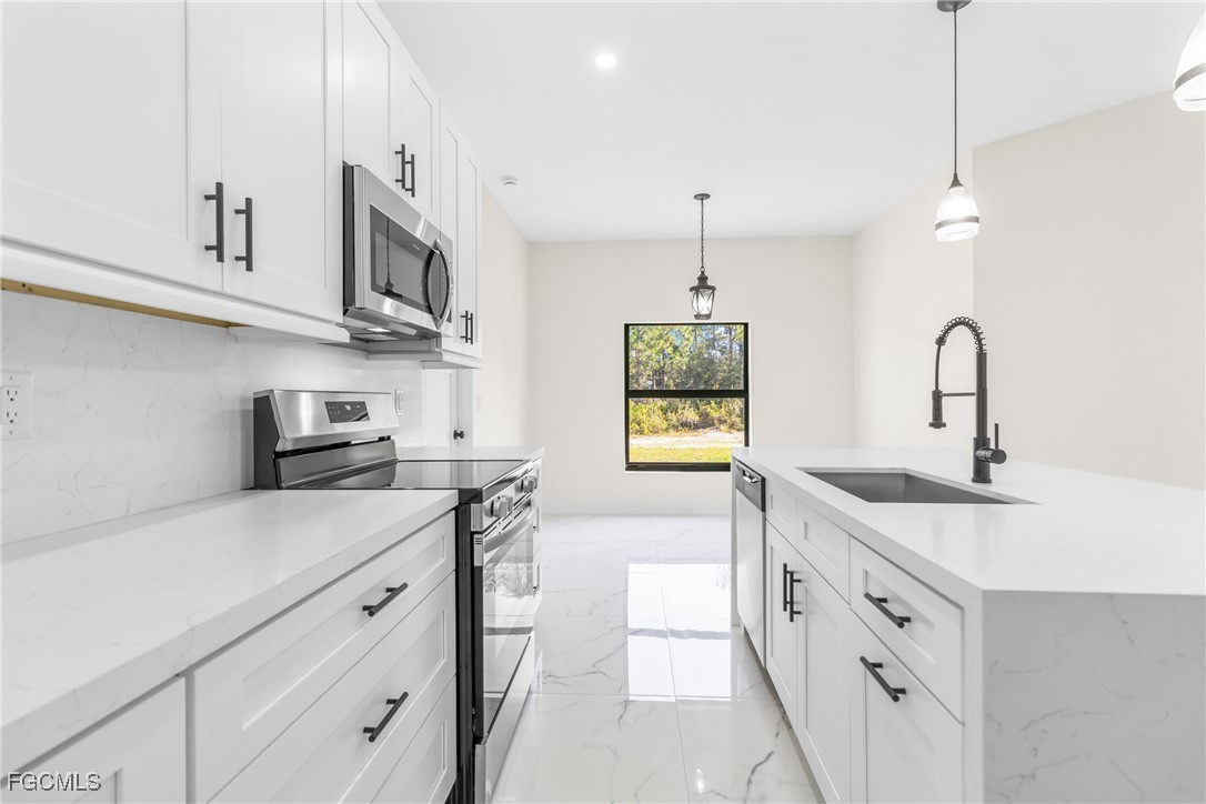 412 Fitch Avenue Lehigh Acres, FL 33972 - Photo 16 of 50 a kitchen with stainless steel appliances granite countertop a sink a stove and a wooden floors