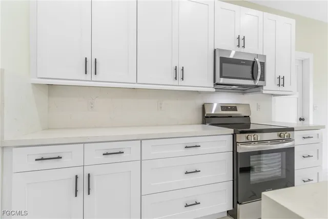a kitchen with white cabinets and stainless steel appliances