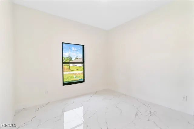 an empty room with a window and a dresser