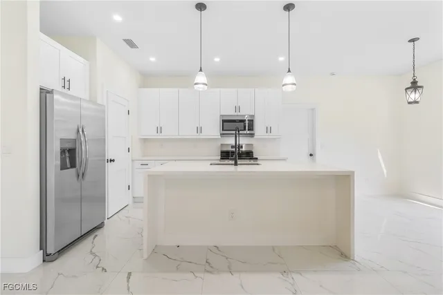 a view of a kitchen with stainless steel appliances granite countertop a refrigerator a oven and a sink