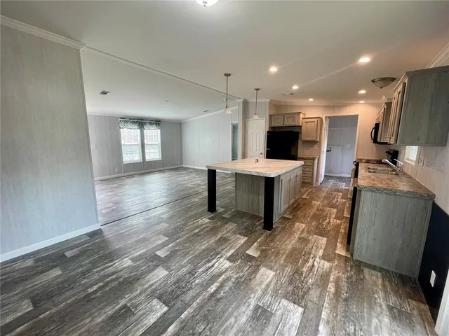 a large kitchen with granite countertop a refrigerator oven a sink dishwasher and wooden cabinets