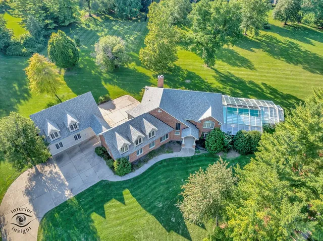 an aerial view of residential house with outdoor space and trees all around