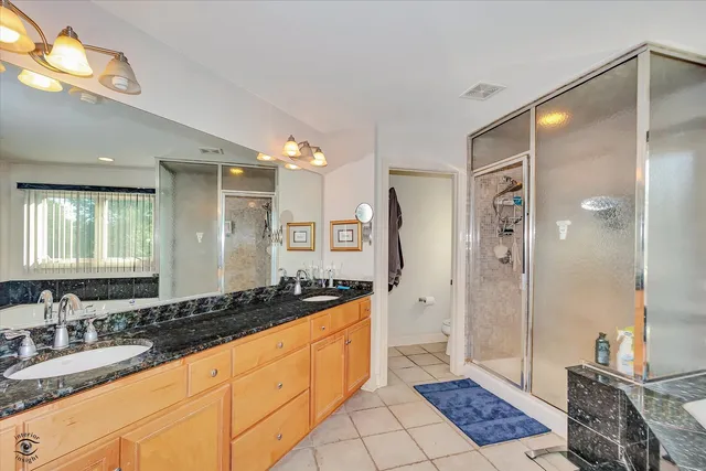 a spacious bathroom with a double vanity sink a mirror and a shower
