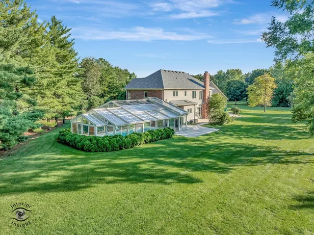 a view of a big house with a big yard plants and large trees