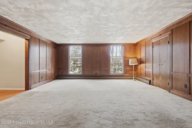 a view of an empty room with chandelier fan and wooden floor