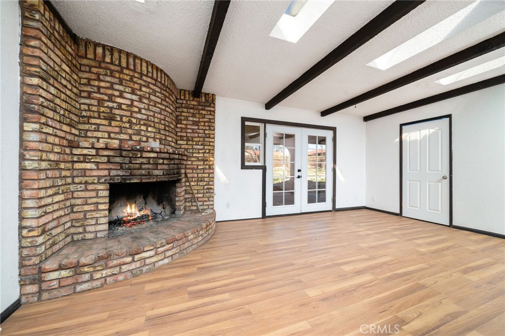 14580 Keota Road Apple Valley, CA 92307 - Photo 16 of 44 a view of empty room with wooden floor and fireplace
