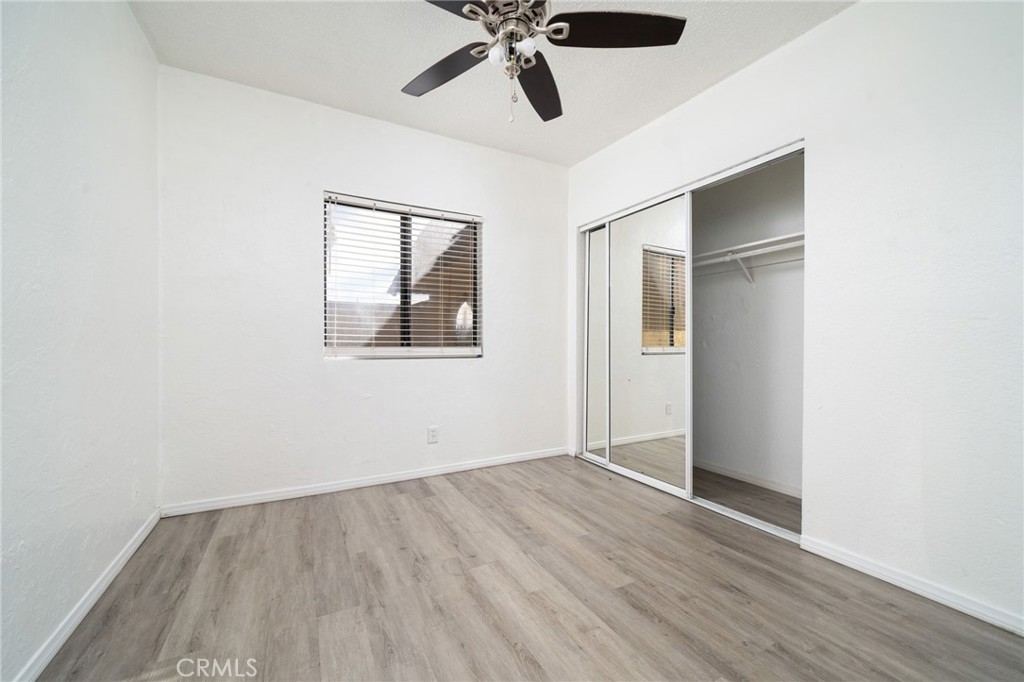 14580 Keota Road Apple Valley, CA 92307 - Photo 24 of 44 an empty room with wooden floor ceiling fan and windows