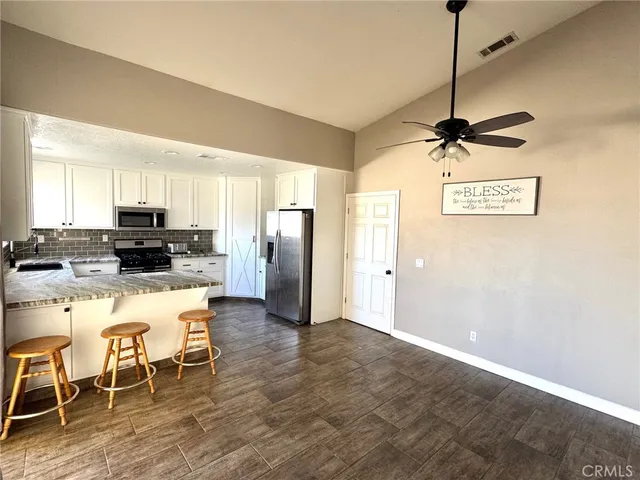 a kitchen with stainless steel appliances granite countertop a refrigerator a stove a sink a dining table and chairs with wooden floor