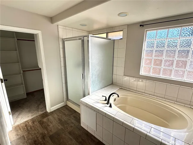 a bathroom with a tub a sink a window and a shower