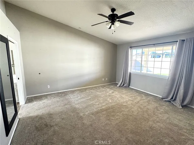 an empty room with windows and fan
