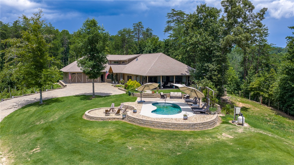 183 Little Eastatoee Road Sunset, SC 29685 - Photo 18 of 50 A spacious home with a well-maintained lawn, inviting pool, and a dedicated fire pit area.