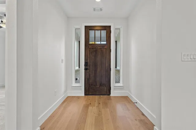 a view of an empty room with wooden floor and closet