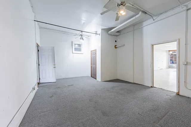 an empty room with a chandelier fan and windows