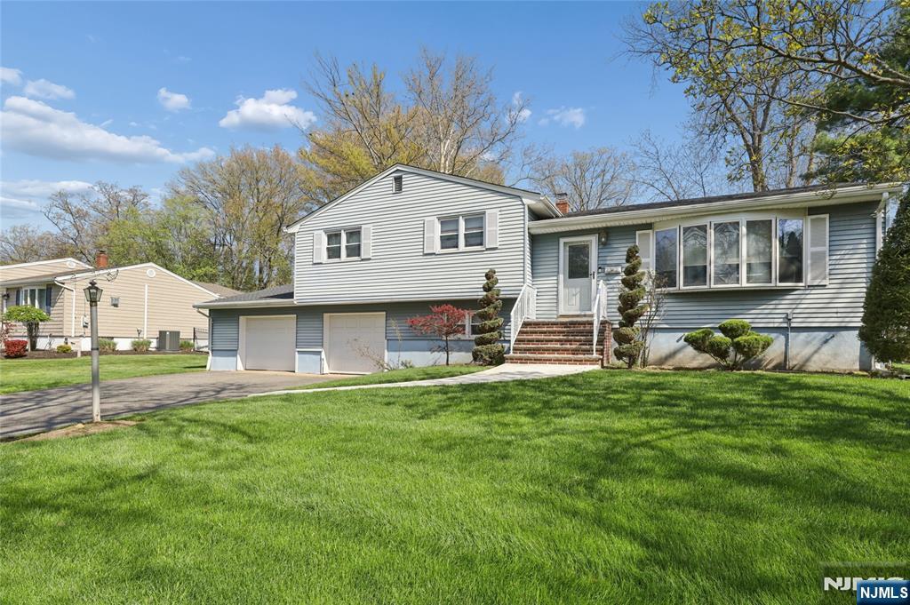 a front view of house with yard and trees in the background