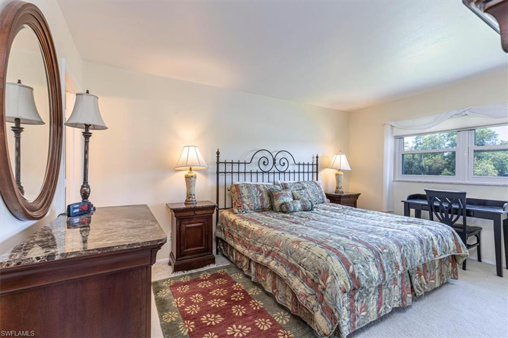 5483 Rattlesnake Hammock Road, Unit B201 Naples, FL 34113 - Photo 11 of 22 a bedroom with a bed a dresser with mirror and window