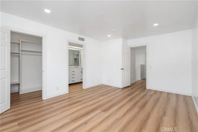 a view of an empty room with wooden floor and closet