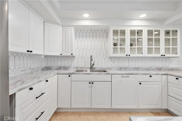 a kitchen with granite countertop white cabinets and sink