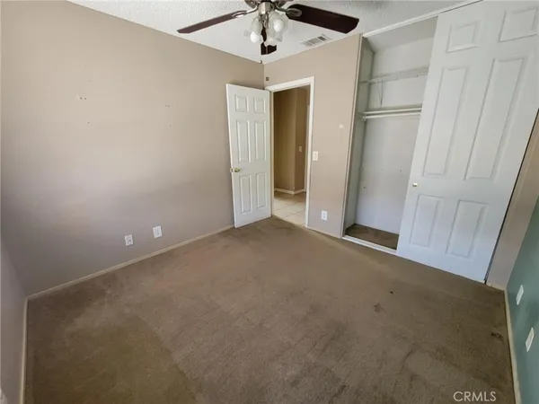 an empty room with a ceiling fan and carpet