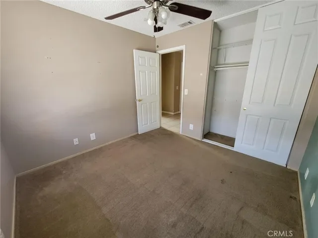 an empty room with a ceiling fan and carpet