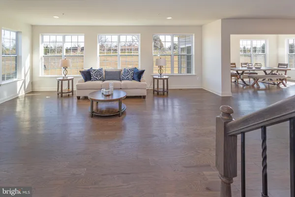 a living room with couches and kitchen view with wooden floor