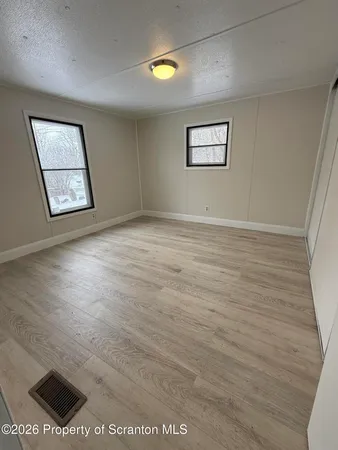 a view of a big room with wooden floor and windows