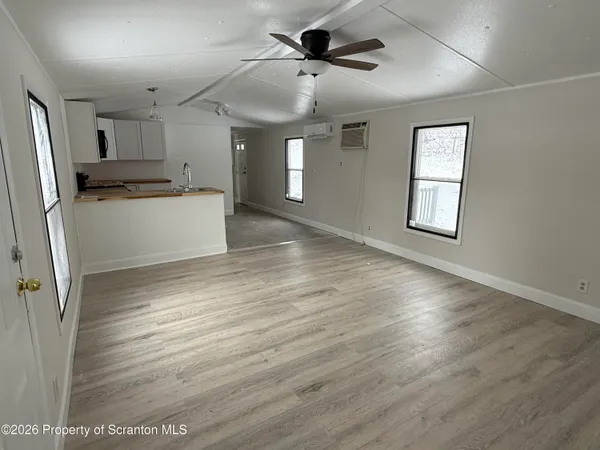 a view of an empty room with window and wooden floor