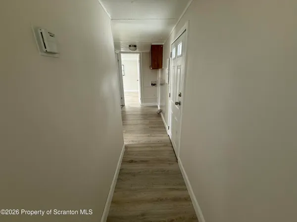 a view of a hallway with wooden floor and a bathroom