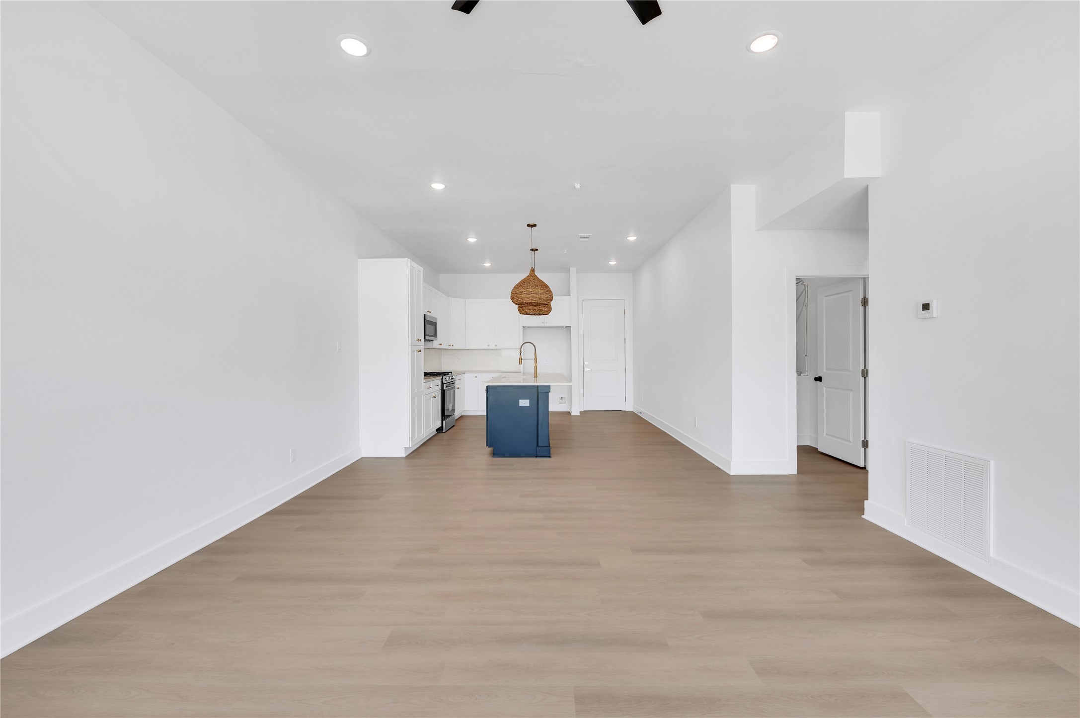 119 Kirby Road, Unit 5205 Seabrook, TX 77586 - Photo 9 of 46 Spacious open-plan living area with sleek wood flooring, modern recessed lighting, and a stylish kitchen featuring a central island and contemporary fixtures.