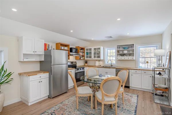 a kitchen with stainless steel appliances a white table chairs and a refrigerator
