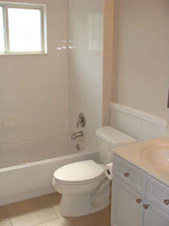 a white toilet and a bath tub sitting next to a white cabinet