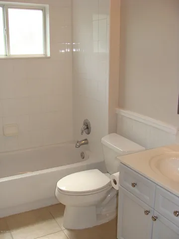 a white toilet and a bath tub sitting next to a white cabinet