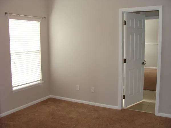 a view of an empty room with closet and a window
