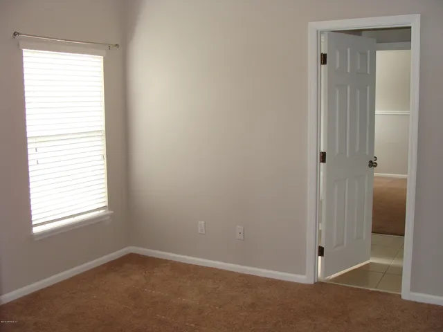 a view of an empty room with closet and a window