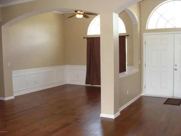 an empty room with wooden floor and windows